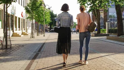 Two people walking and talking down a street